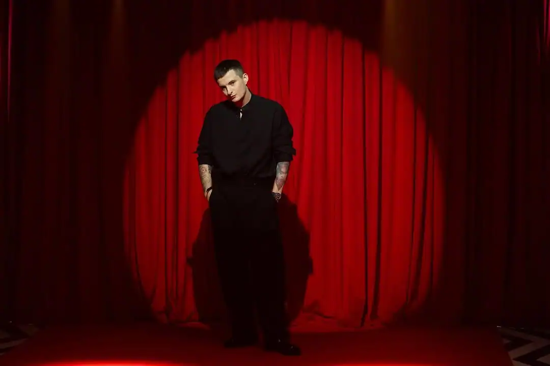 злой стример в черном у красного занавеса фото